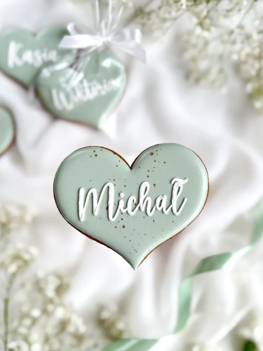 Piernik na komunię w kształcie serca z imieniem zapakowany w celofanowy woreczek z kokardką jako forma podziękowania dla gości komunijnych