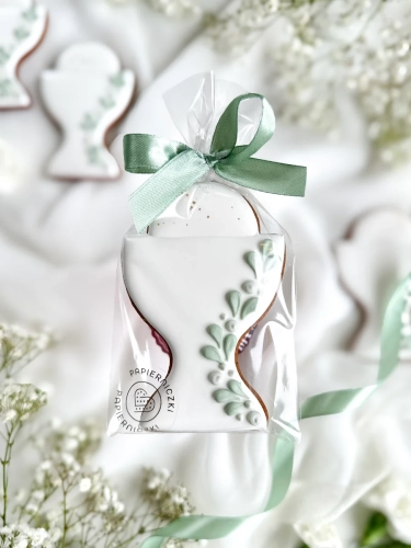 Piernik na komunię w kształcie kielicha z gałązką zapakowany w celofanowy woreczek z kokardką jako forma podziękowania dla gości komunijnych