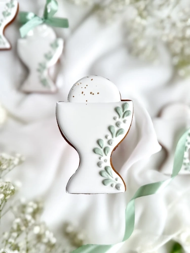 Piernik na komunię w kształcie kielicha z gałązką zapakowany w celofanowy woreczek z kokardką jako forma podziękowania dla gości komunijnych