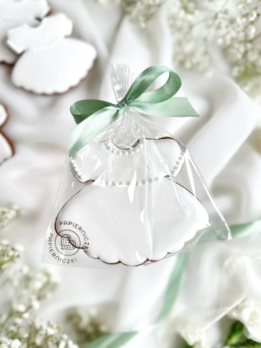 Piernik na komunię w kształcie sukienki zapakowany w celofanowy woreczek z kokardką jako forma podziękowania dla gości komunijnych