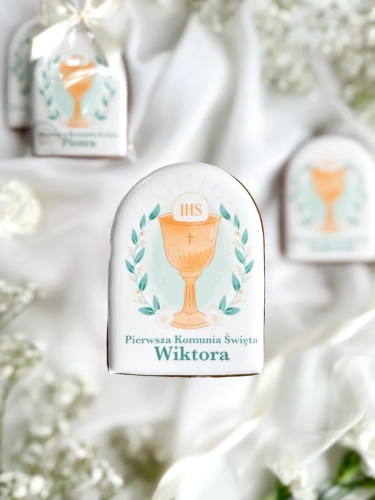 Piernik na komunię z grafiką kielicha i personalizowanym napisem zapakowany w celofanowy woreczek z kokardką jako forma podziękowania dla gości komunijnych