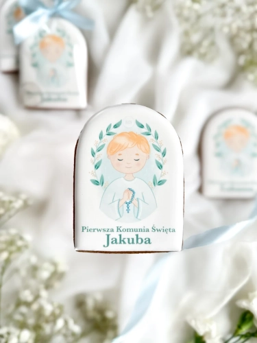Piernik na komunię z grafiką chłopca i personalizowanym napisem zapakowany w celofanowy woreczek z kokardką jako forma podziękowania dla gości komunijnych