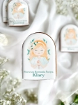 Piernik na komunię z grafiką dziewczynki i personalizowanym napisem zapakowany w celofanowy woreczek z kokardką jako forma podziękowania dla gości komunijnych