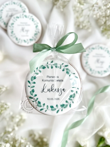 Piernik na komunię z grafiką wianka i personalizowanym napisem zapakowany w celofanowy woreczek z kokardką jako forma podziękowania dla gości komunijnych