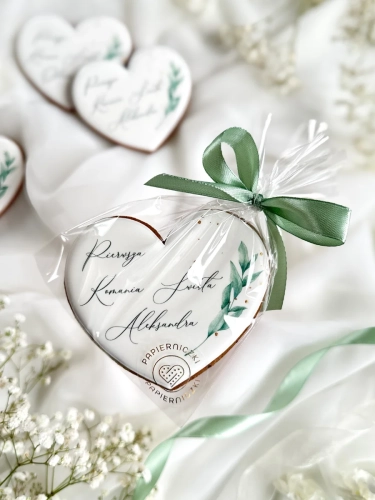 Piernik na komunię w kształcie serca z grafiką gałązki, ze złoceniem i personalizowanym napisem zapakowany w celofanowy woreczek z kokardką jako forma podziękowania dla gości komunijnych
