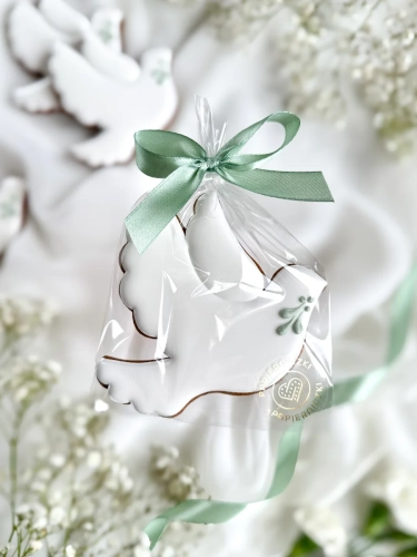 Piernik na komunię w kształcie gołąbka z gałązką zapakowany w celofanowy woreczek z kokardką jako forma podziękowania dla gości komunijnych